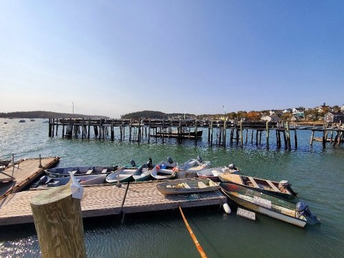 A serene waterfront scene with boats docked at a pier under a clear blue sky.