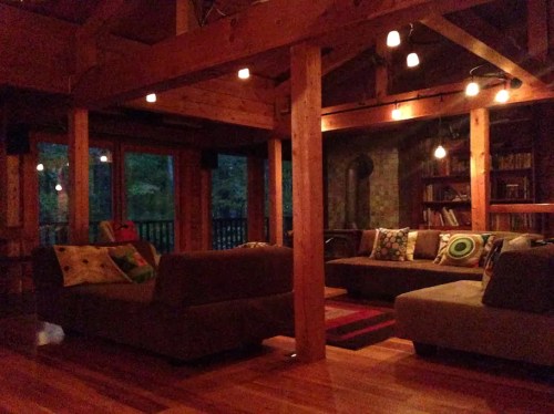 Cozy living room with wooden beams, soft lighting, and comfortable sofas adorned with colorful pillows.