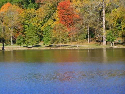 A serene lake reflecting vibrant autumn trees in shades of red, orange, and green.