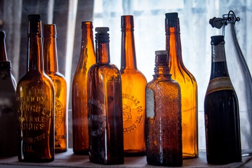 A collection of vintage amber glass bottles arranged on a table, illuminated by soft natural light.