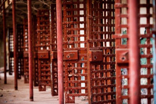 A series of rusted metal bars create a pattern in an abandoned building, evoking a sense of decay and neglect.