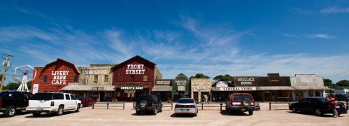 A western-style town with colorful buildings, including a saloon and general store, under a clear blue sky.