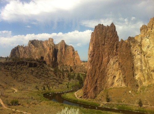 A scenic view of rugged rock formations beside a winding river under a partly cloudy sky.