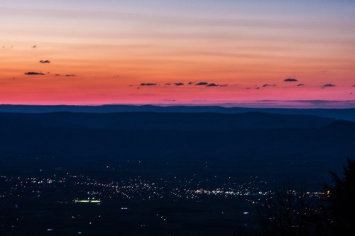 A serene sunset over distant mountains, with a gradient of pink and orange hues illuminating the sky.
