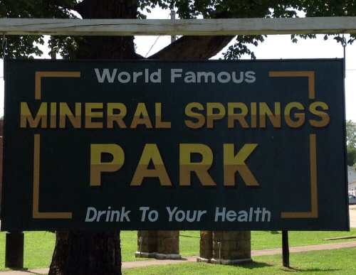 Sign for Mineral Springs Park, featuring the text "World Famous" and "Drink To Your Health" in bold letters.