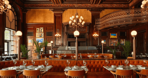 Elegant restaurant interior featuring ornate woodwork, plush seating, and decorative chandeliers.