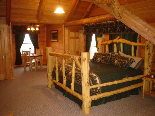 Cozy wooden cabin interior featuring a log bed, dining area, and warm lighting.