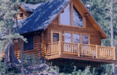 A cozy wooden cabin with a balcony, surrounded by trees and nature.