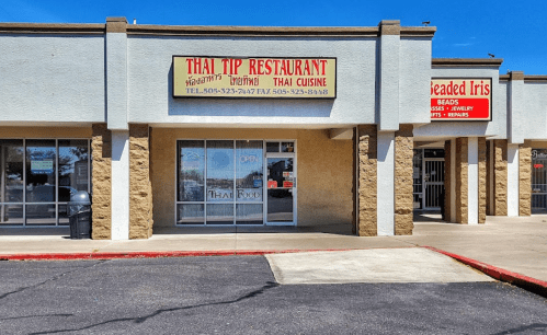 Exterior of a Thai restaurant with a bright sign reading "Thai Tip Restaurant" and an "Open" sign in the window.