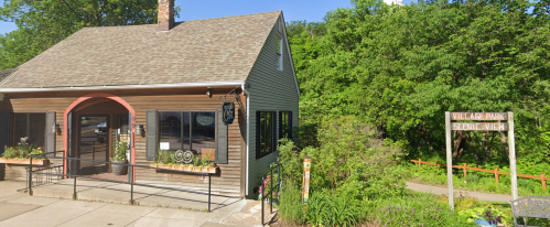 A quaint building with a sloped roof, featuring large windows and a sign for Village Park Scenic View nearby.