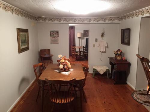 A cozy dining area with a wooden table, chairs, and decorative items, featuring soft lighting and a warm atmosphere.