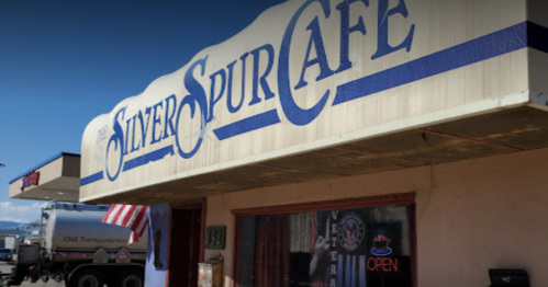 Sign for the Silver Spur Café, featuring an "Open" sign and an American flag outside.