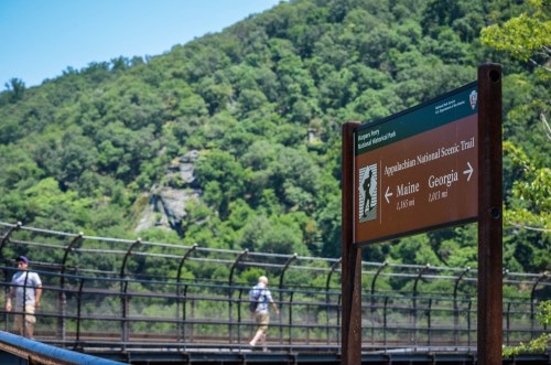 Sign for the Appalachian National Scenic Trail with directions to Maine and Georgia, set against a lush green background.