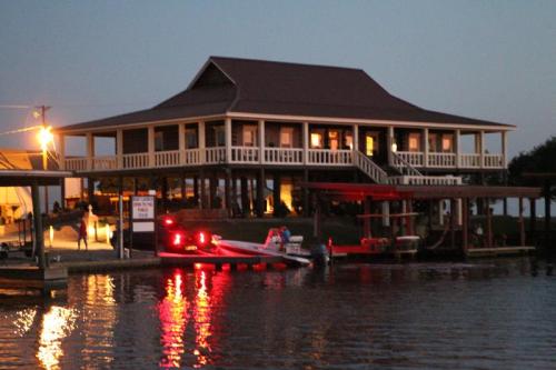 A waterfront house at dusk, with a boat docked nearby and lights reflecting on the water.