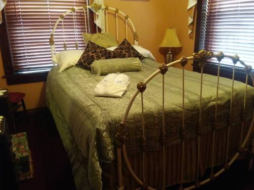 A cozy bedroom featuring a vintage metal bed with green bedding, decorative pillows, and warm lighting.