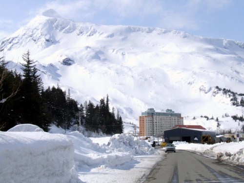 A snowy mountain landscape with a road leading to a hotel surrounded by snow-covered trees.
