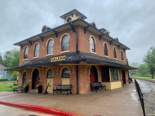 Historic Galena train station with brick architecture, arched windows, and a covered platform on a rainy day.