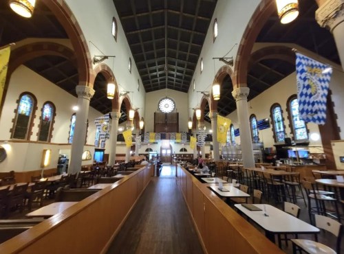 Interior of a spacious restaurant with high ceilings, stained glass windows, and decorative banners.