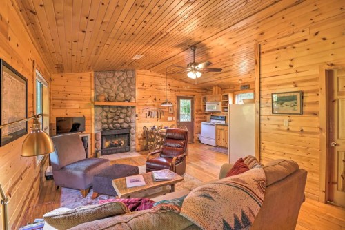 Cozy wooden cabin interior featuring a stone fireplace, comfortable seating, and a warm, inviting atmosphere.