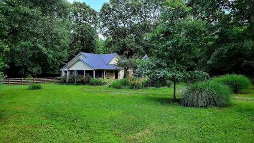 A charming house surrounded by lush greenery and colorful flowers in a serene, natural setting.