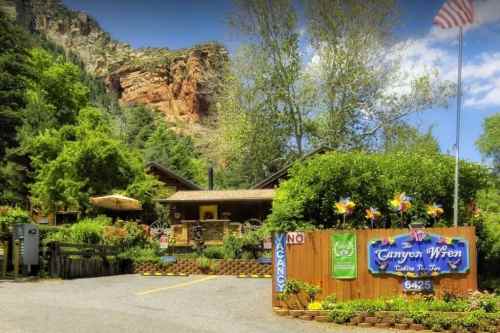 A welcoming lodge surrounded by greenery, with a sign reading "Canyon Wren" and a flag in the background.
