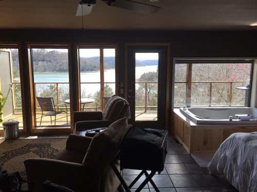 Cozy interior with a view of a lake, featuring a hot tub, seating area, and large windows.