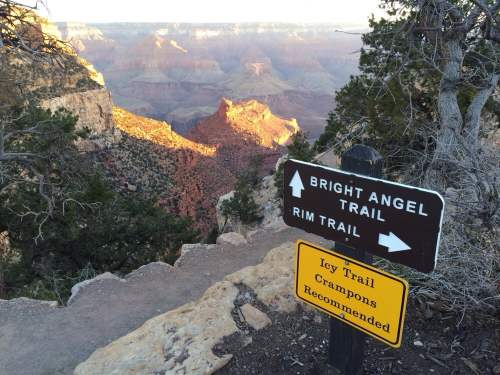 Signpost at the Grand Canyon indicating Bright Angel Trail and Rim Trail, with a warning for icy conditions ahead.