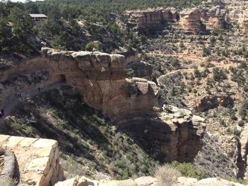 A rocky canyon landscape with steep cliffs, greenery, and a winding path along the edge.