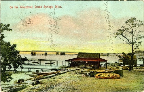 Vintage postcard depicting a waterfront scene in Ocean Springs, Mississippi, with boats and a serene sunset.