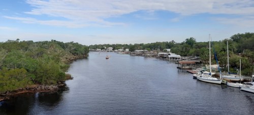 A calm river lined with trees and docks, featuring boats and a clear blue sky.