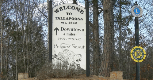 Welcome sign for Tallapoosa, established 1860, with directions to downtown and an illustration of a possum.