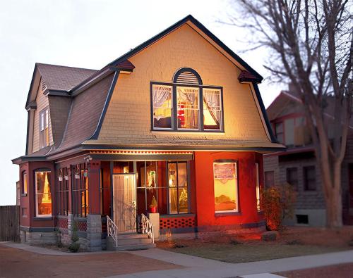 A charming two-story house with a gabled roof, warm lighting, and decorative windows, set in a quiet neighborhood.