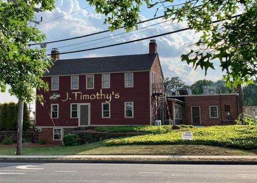 A red building with "J. Timothy's" painted on the side, surrounded by greenery and power lines.