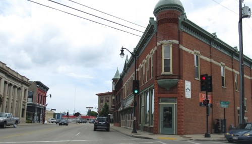Historic brick buildings at an intersection with traffic lights and a cloudy sky.