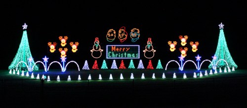 Colorful Christmas light display featuring trees, snowmen, and a "Merry Christmas" sign against a dark background.