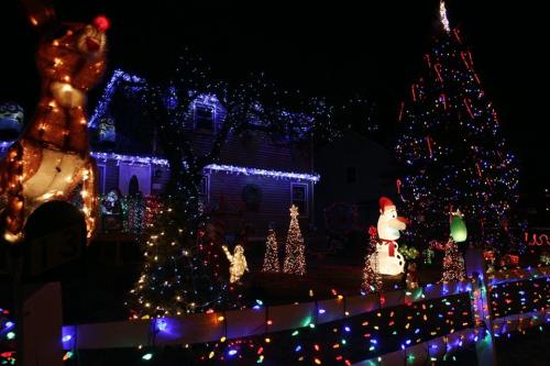 A festive display of colorful Christmas lights, featuring a decorated tree, snowman, and various holiday figures.