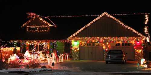 A house decorated with colorful Christmas lights and festive decorations, glowing brightly against a dark night sky.