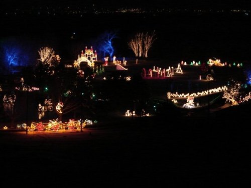 A colorful display of holiday lights illuminating a park at night, featuring various festive decorations and scenes.