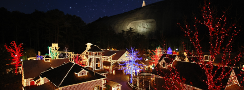 A festive scene of a village illuminated with colorful Christmas lights against a starry night sky.