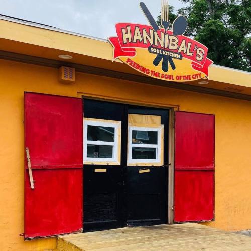 Exterior of Hannibal's Soul Kitchen, featuring a colorful sign and boarded-up windows, with a wooden deck in front.