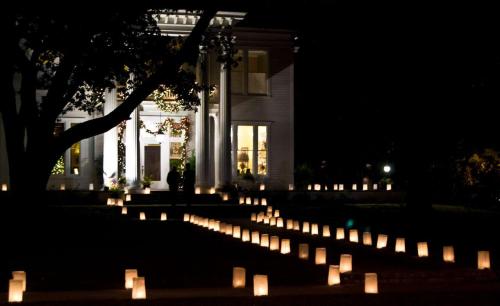 A beautifully lit historic house at night, surrounded by glowing lanterns along a winding path.