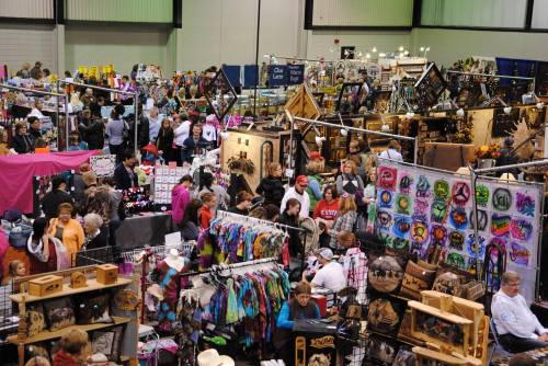 A bustling craft fair with numerous booths displaying colorful handmade items and a crowd of shoppers exploring.