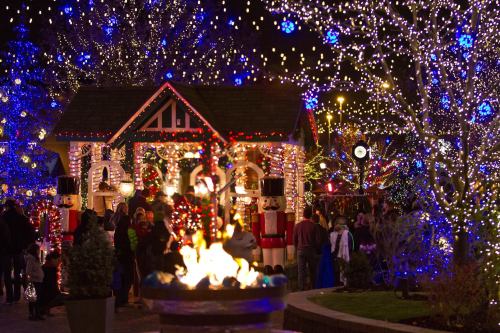 A festive scene with a decorated house, nutcracker figures, and colorful lights illuminating a winter gathering.