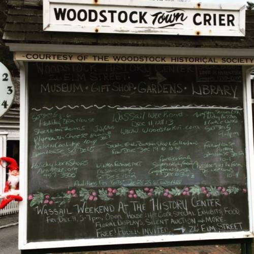 A chalkboard sign listing events and information for the Woodstock Historical Society, including a holiday weekend.