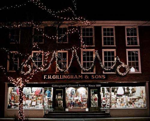 A festive storefront decorated with lights and wreaths, featuring a sign for F.H. Gillingham & Sons General Store.