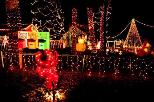 Colorful holiday lights illuminate a festive outdoor scene with decorations, including snowmen and a Christmas tree.