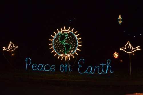 Colorful holiday lights display featuring the Earth and the words "Peace on Earth" with decorative elements.