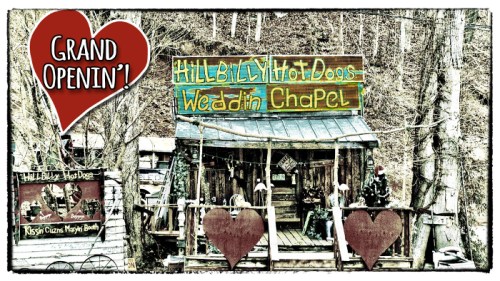 A rustic building with signs for "Hillbilly Hot Dogs" and "Wedding Chapel," decorated with hearts for a grand opening.