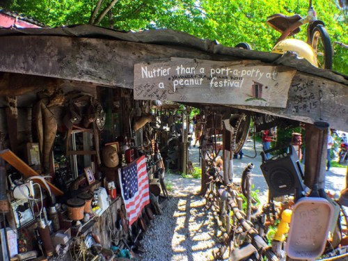 A quirky outdoor display with various items and a sign reading, "Nuttier than a porta-potty at a peanut festival."