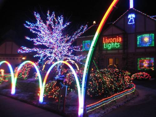 A brightly lit house decorated with colorful Christmas lights, featuring a glowing tree and festive arches.